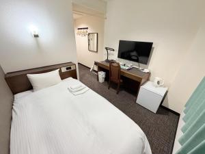 a hotel room with a bed and a desk with a television at Hotel Tetora HonHachinohe in Hachinohe +14 photos