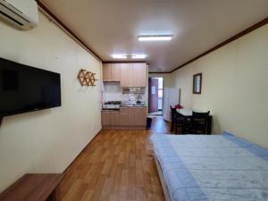 a living room with a television and a kitchen at 속초푸른바다펜션 in Puwŏl-li