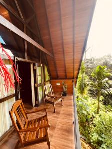 a porch of a house with two wooden chairs at Rainforest Emerald Haven in Deniyaya