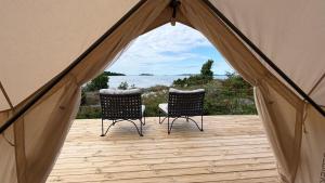 Zwei Stühle stehen auf einer Terrasse in einem Zelt in der Unterkunft Seglinge Glamping in Norrön