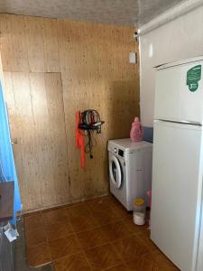 a small kitchen with a refrigerator and a washing machine at Jumgal Nomad House in Kyzart