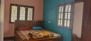 a bed in a room with two windows at Thendral Falls View Homestay in Kuttālam