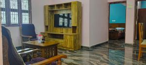 a room with a wooden book shelf and a table at Thendral Falls View Homestay in Kuttālam