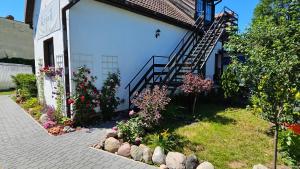 a white building with a door and some flowers at Keja II in Łeba