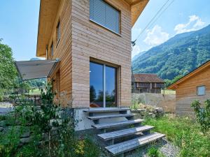 a house with stairs next to a building with mountains at Holz100 Kleinhaus in Attinghausen