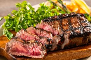 a piece of steak on a cutting board with a salad at Spa Resort Hawaiians VIR Port in Iwaki