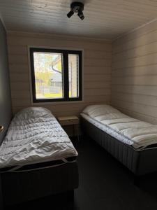 two beds in a room with a window at Himos Siesta Porealtaalla ja loppusiivouksella in Jämsä