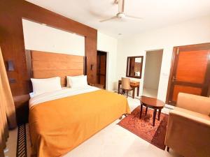 a bedroom with a bed and a table and a chair at Comfort Lodge Executive in Islamabad