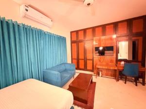 a bedroom with a bed and a couch and a desk at Comfort Lodge Executive in Islamabad