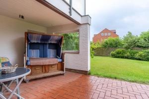 a patio with a bed and a table and a window at Romantica EG in Sankt Peter-Ording
