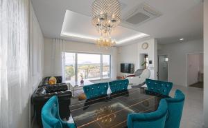 a living room with blue chairs and a chandelier at 판포홈치풀빌라 in Wŏllyŏng