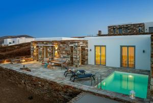 a patio with a swimming pool next to a house at Villa Plora, by Estia in Áno Meriá