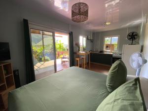 a bedroom with a bed and a kitchen with a view at Fare Maraea in Moorea