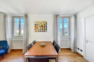 a dining room with a wooden table and two windows at La Piazza Menaggio in Menaggio