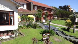 a building with a yard with stairs and flowers at Hotel Mariska Dos Estrellas Superior in Villa Gesell
