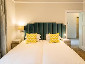 a bedroom with a large bed with two yellow pillows at Boschhuis Apartments - Stellenbosch in Stellenbosch