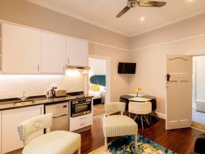 a kitchen with white cabinets and a table with chairs at Boschhuis Apartments - Stellenbosch in Stellenbosch