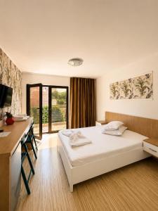 a bedroom with a bed and a desk and a window at Casa Maxim Eforie Nord in Eforie Nord