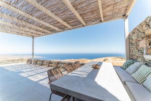 a patio with a table and chairs and the ocean at Ayelma - Kythnos Villa in Kithnos