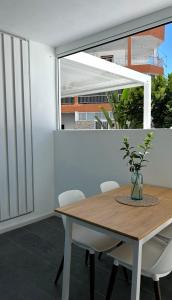 a dining room with a wooden table and white chairs at BeachVibe in Puerto Naos