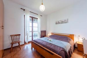 a bedroom with a bed and a chair and a window at Lago Azzurro Villa: Infinity Lake View - Happy Rentals in Premeno