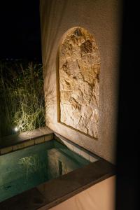a pool of water with a stone wall and a window at Mount Valley Inn in Kubupenlokan +12 photos