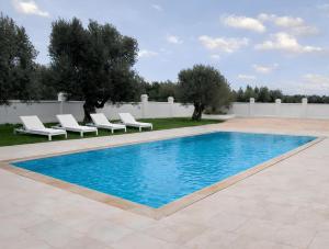 a swimming pool with lounge chairs and a fence at Masseria Lama D'impisa in Fasano