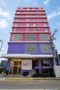 ein großes rosa und lila Gebäude mit einem Hotel-MMO-Schild in der Unterkunft Hotel Mó -Taguig in Manila
