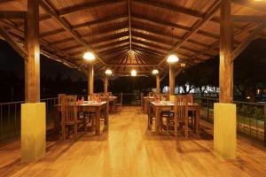 a restaurant with wooden tables and chairs under a wooden ceiling at Villa Oasis in Kataragama