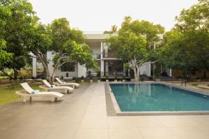 a swimming pool with lounge chairs and a building at Villa Oasis in Kataragama