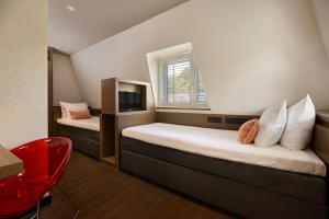 a bedroom with two beds with a window and a red chair at Van der Valk Hotel de Bilt-Utrecht in De Bilt