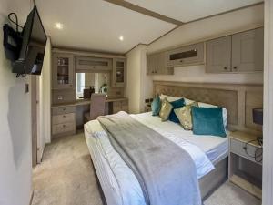 a bedroom with a large bed with blue pillows at Abi Beaumont - Ty Mawr in Rowen