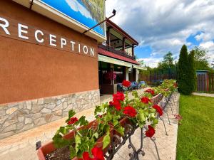 a row of benches with red flowers outside of a restaurant at Tryavna Lake Hotel & SPA in Tryavna