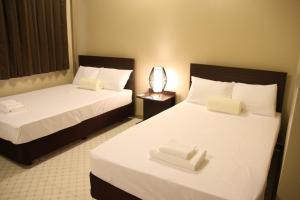2 bedden in een hotelkamer met witte lakens bij DW Motel in Koror