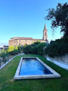 a swimming pool in the grass with a church in the background at Maison La Julianne in Callas