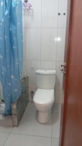 a bathroom with a toilet with a blue shower curtain at Pati place in Mememo