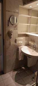 a white bathroom with a sink and a mirror at WAGNERS Hotel im Bayerischen Wald in Grafenau +10 photos