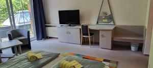 a living room with a desk and a television at WAGNERS Hotel im Bayerischen Wald in Grafenau