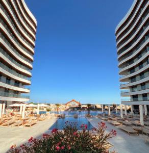 two tall buildings with a swimming pool next to a beach at Apartament Marreo Casa del Mar in Mamaia
