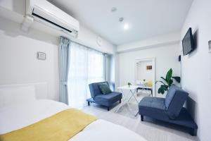 a bedroom with a bed and two chairs and a table at Montana Flat Yebisu in Osaka