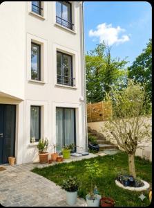 a white house with a yard with potted plants at House in Clamart
