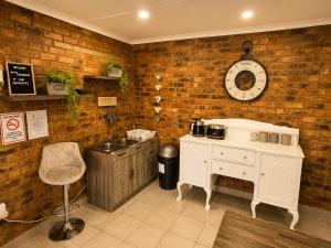 a kitchen with a counter and a clock on a brick wall at Zhantique Guest House 1- Unit 3 in Boksburg