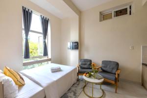 a bedroom with a bed and two chairs and a window at G8 Le Van Sy Hotel Saigon in Ho Chi Minh City +25 photos