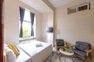 a bedroom with a bed and a chair and a window at G8 Le Van Sy Hotel Saigon in Ho Chi Minh City