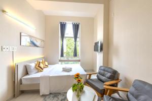 a bedroom with a bed and a chair and a window at G8 Le Van Sy Hotel Saigon in Ho Chi Minh City