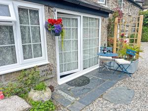 a patio with a table and two windows at Mole Cottage - Uk52139 in Liskeard