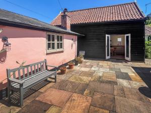 a pink house with a bench on a patio at The Cottage in Chelsworth