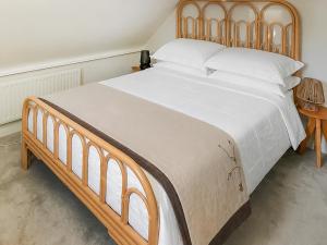 a large bed with a wooden headboard in a bedroom at The Cottage in Chelsworth