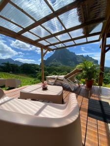 a deck with a pergola with a view of mountains at Fare Maraea Iti in Moorea