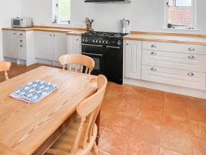 a kitchen with a wooden table and a black stove at The Cottage in Chelsworth +9 photos